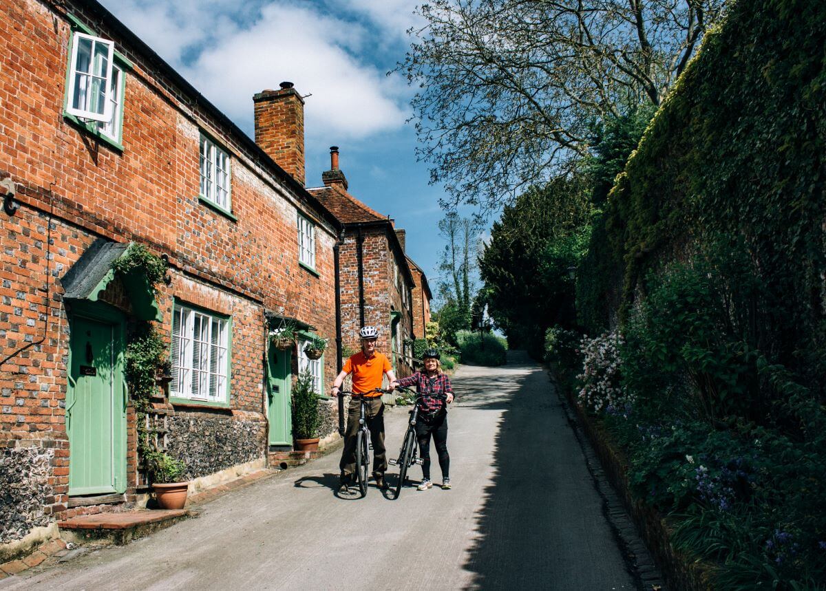 Two cyclists in a quaint village street of red bricked houses