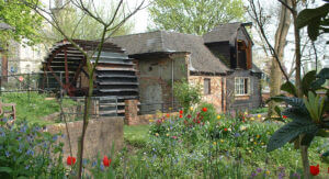 Pann Mill showing the large wooden waterwheel and a beautiful cottage garden in the foreground