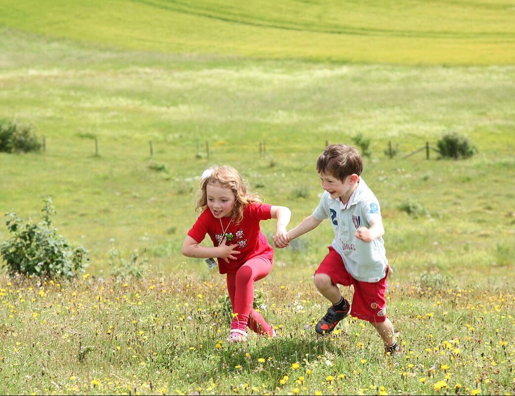 Children running in a flower meadow