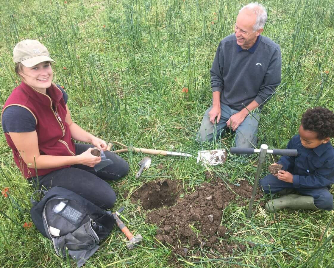 Two adults and a child taking samples for soil carbon assessments