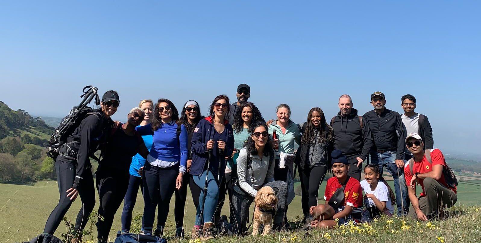 A group of walkers pose for a photo at the top of a hill.