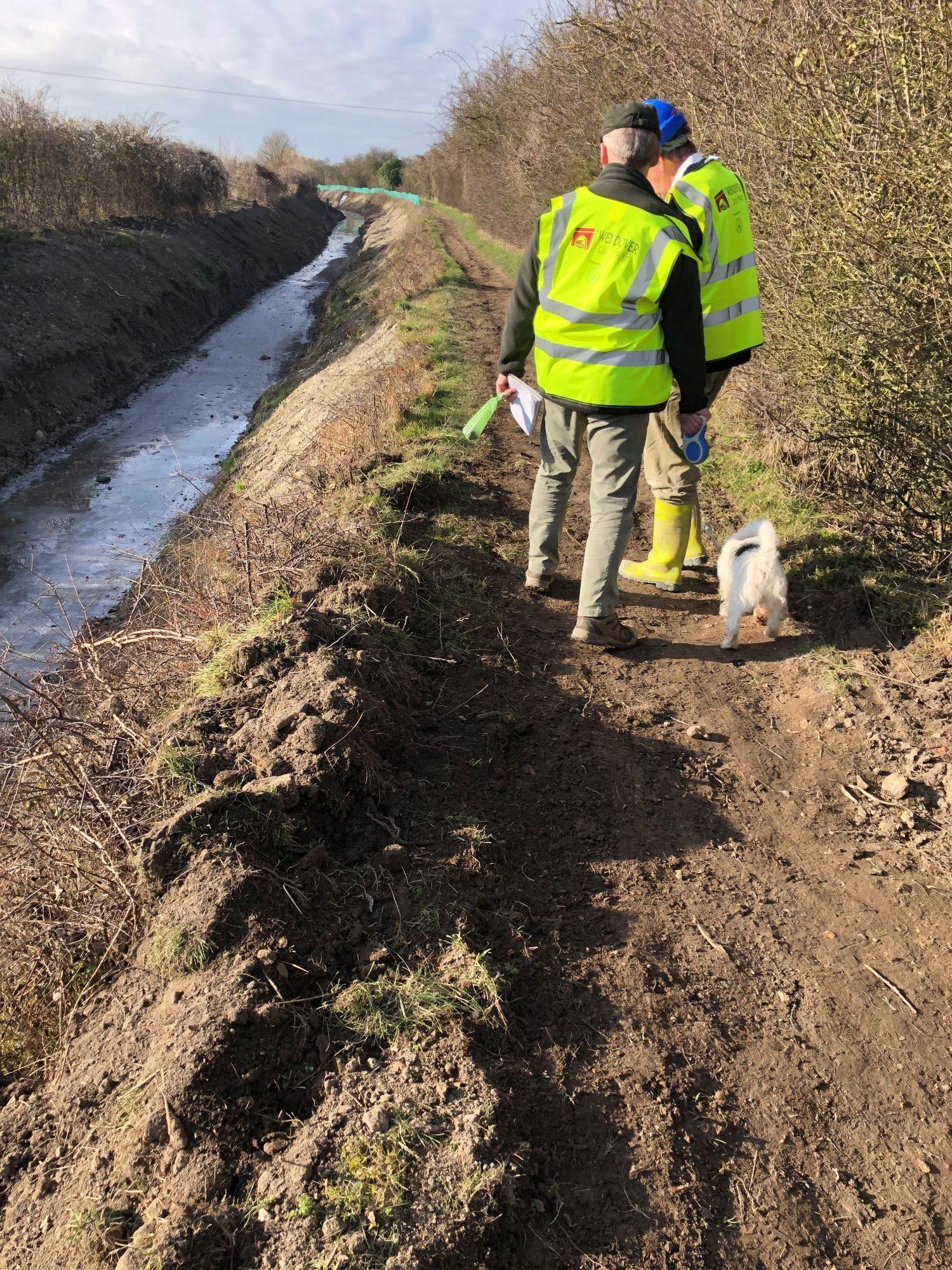 A photo of Workmen at the side of a canal resurfacing the towpath