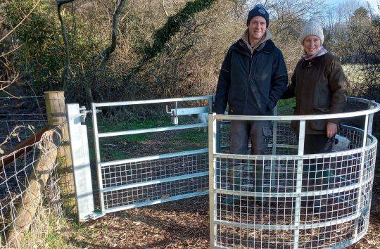 Two people going through a newly installed accessible gate at Bolt Hole Farm.