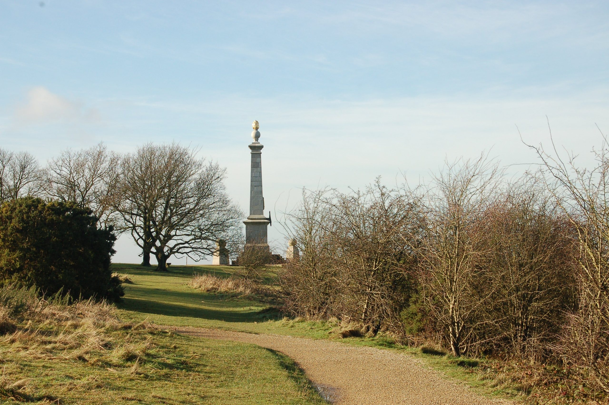 A stone monument sits on top of a hill surrounded by grassland and shrubs.