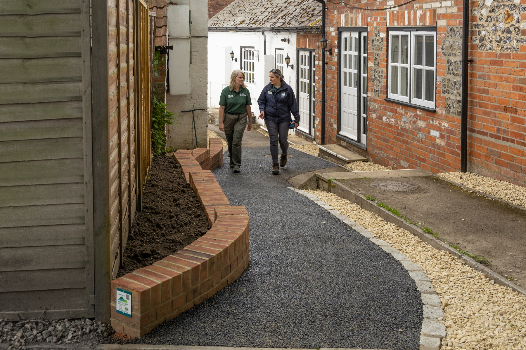 Two women walk on a new footpath.
