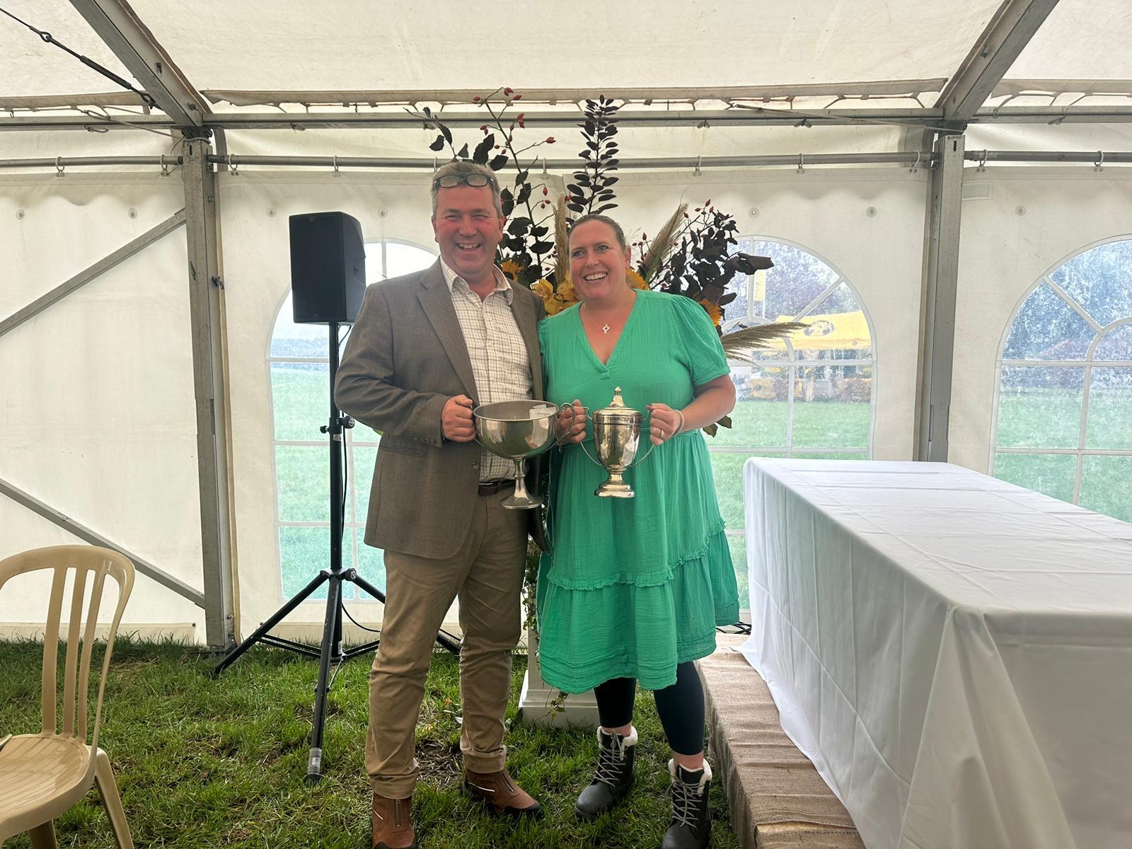 A man and woman holding trophies.