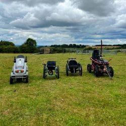 Four mobility scooters and all terrain trampers in a green field