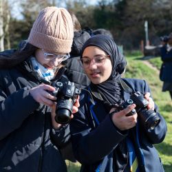 two girls comparing photos on their digital cameras