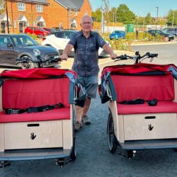 A man posing with two adapted trishaws