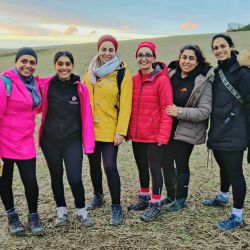a group of women standing together in the countryside smiling