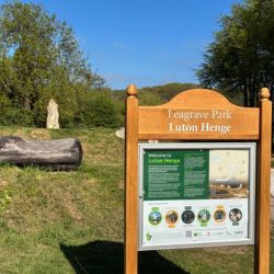 A wooden information board placed in front of Luton Henge stone