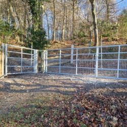 A wide metal gate in woodland
